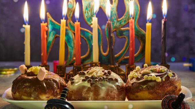 jewish-holiday-hanukkah-traditional-dish-is-sweet-donuts-hanukkah-table-setting-candlestick-with-candles-spinning-tops-lighting-chanukah-candles-min