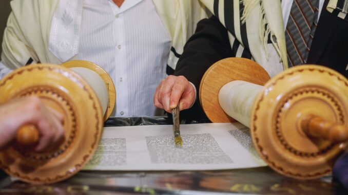 praying-man-with-tefillin-on-his-arm-and-head-holding-torah-while-reading-pray-min